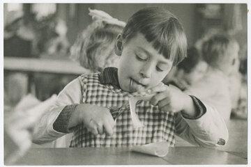 Garçon pratiquant une activité manuelle de découpage de papier. 