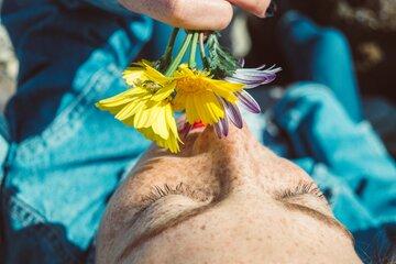 Une personne allongée sent un bouquet de fleurs sauvages