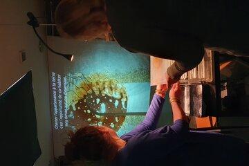 Matière terre agrandie et vue à travers de la lumière, avec une personne en transparence qui s'exclame les mains en l'air. 
