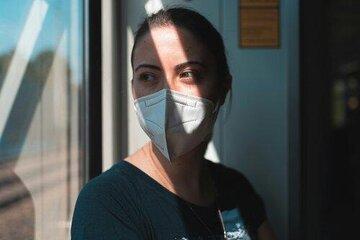 Femme avec un masque près d'une fenêtre