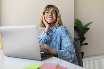 femme-souriante-tir-moyen-travaillant-sur-ordinateur-portable