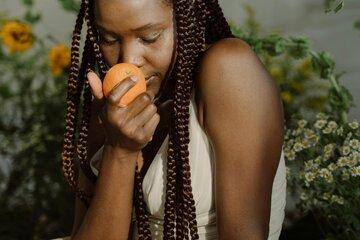 Une jeune fille sent une orange qu'elle tient dans ses mains.