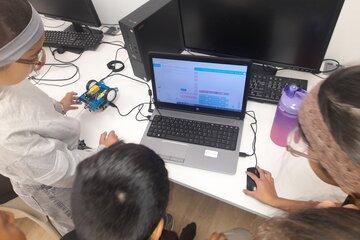 enfants autour d'un portable avec petit robot en train de faire de la programmation