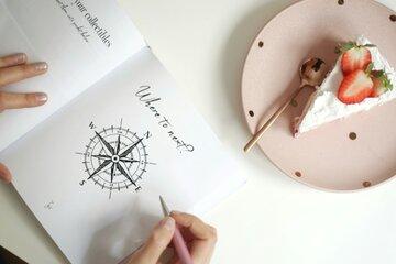 Carnet ouvert main qui écrit et tarte à côté 