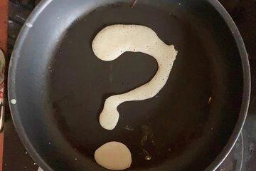 De la pâte à crêpes en forme de point d'interrogation dans une poêle