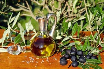 branches d'olivier en arrière plan avec au premier plan des olives noires et de l'huile d'olive