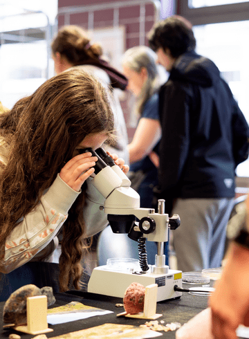 Jeune fille observant dans une loupe binoculaire